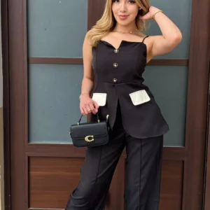 Modelo vistiendo el Conjunto Blazer Peplum de color negro con botones joya y pantalón wide leg de Heredia Showroom