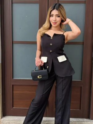 Modelo vistiendo el Conjunto Blazer Peplum de color negro con botones joya y pantalón wide leg de Heredia Showroom